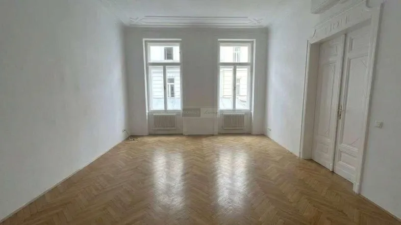 Geräumiges Zimmer mit Fischgrätparkett, hohen Decken, Stuckverzierungen und Klimaanlage, bereit zur Gestaltung.
