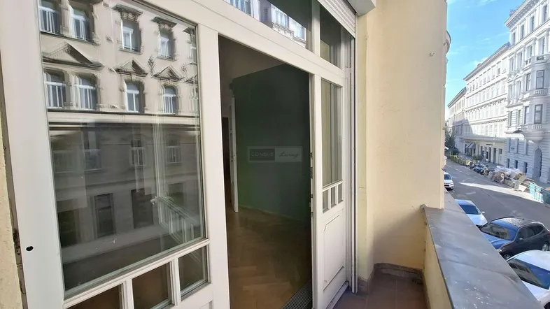 Blick vom Balkon auf die belebte Stadtstraße und den Eingang zum Innenraum der Wohnung.