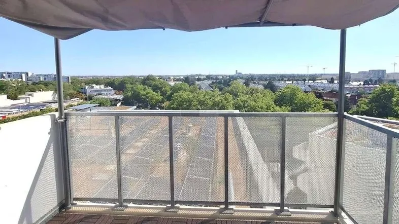 Geräumiger Balkon mit Holzboden und weitem Blick über die Stadt und grüne Umgebung.
