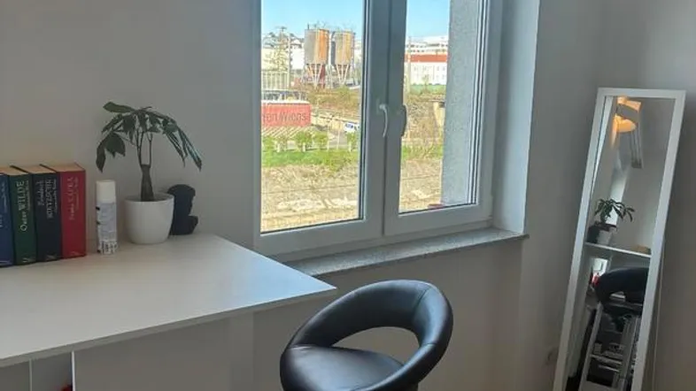 Helles Zimmer mit Bartisch, Barhocker und Fenster, das einen Blick ins Grüne bietet.