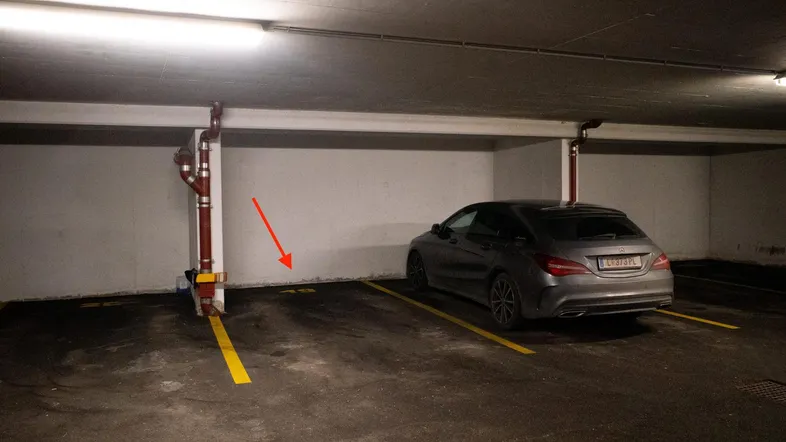 Tiefgaragenstellplatz mit gelben Markierungen und einem geparkten Auto.