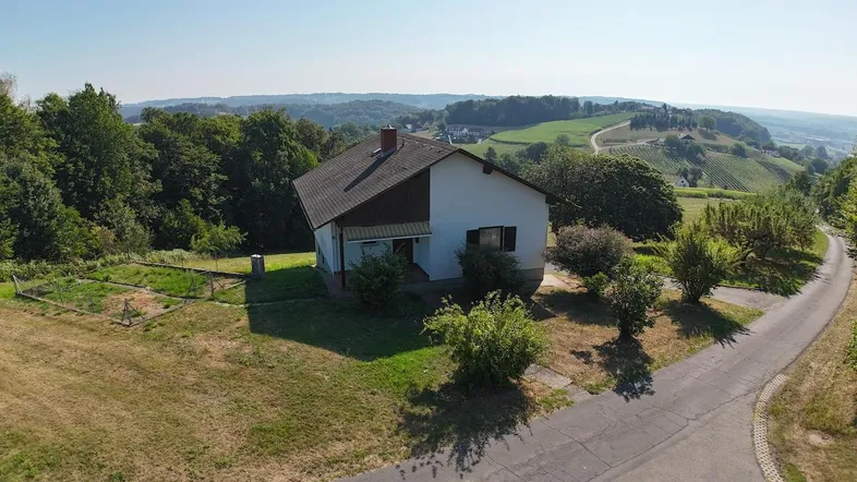 Luftaufnahme eines Einfamilienhauses in ländlicher Umgebung mit weitem Blick über Hügel und Weinberge.