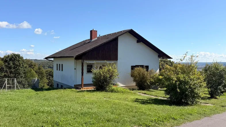 Freistehendes Einfamilienhaus auf einem Hügel mit weitem Blick über die Landschaft und viel Grün.