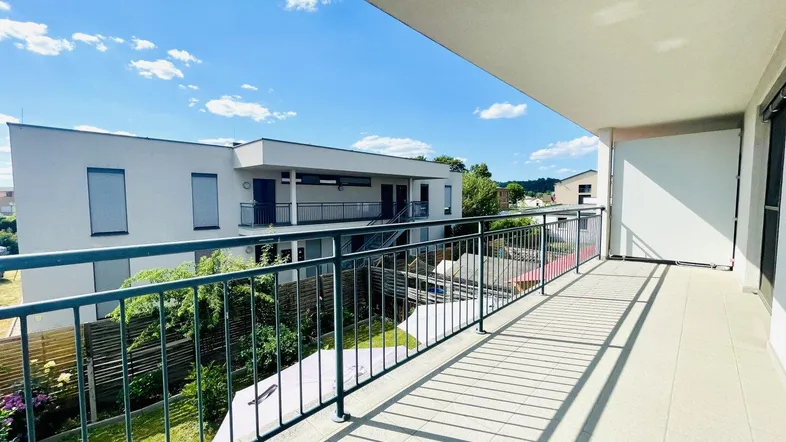 Geräumiger Balkon mit Blick auf die umliegenden Gebäude und einen kleinen Gartenbereich.