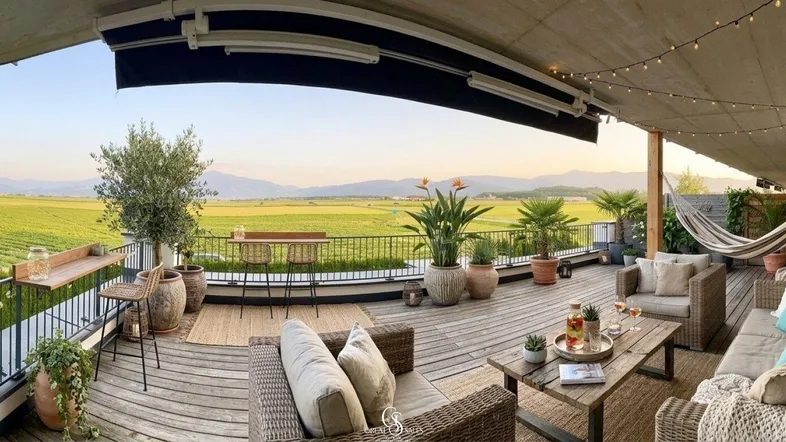 Geräumige Terrasse mit gemütlicher Sitzecke, Hängematte und weitem Blick über Weinberge und Berge.