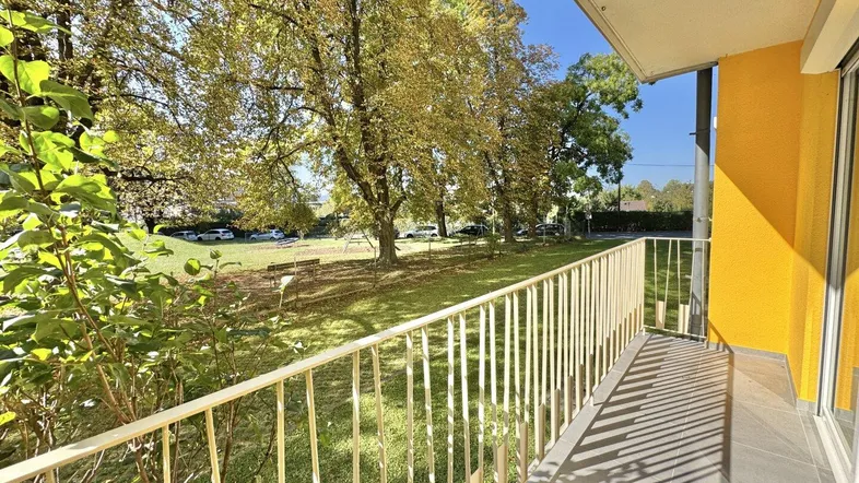 Heller Balkon mit Blick ins Grüne und auf Bäume, ideal zum Entspannen im Freien.