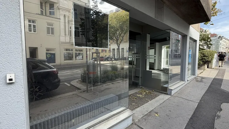 Große Schaufensterfront eines Geschäftsraums, die die gegenüberliegende Straße und Gebäude widerspiegelt.