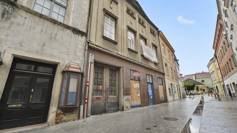 Historische Gebäude säumen eine gepflasterte Gasse, die eine traditionelle Stadtansicht zeigt.