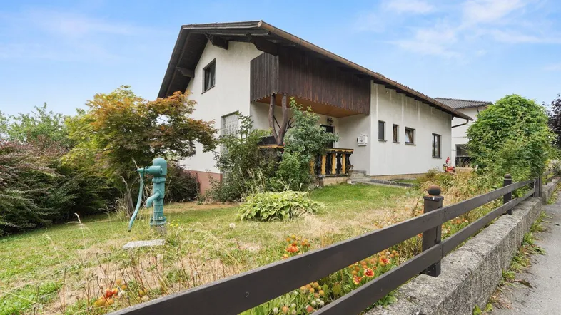 Einfamilienhaus mit Satteldach und Vorgarten in ländlicher Umgebung.