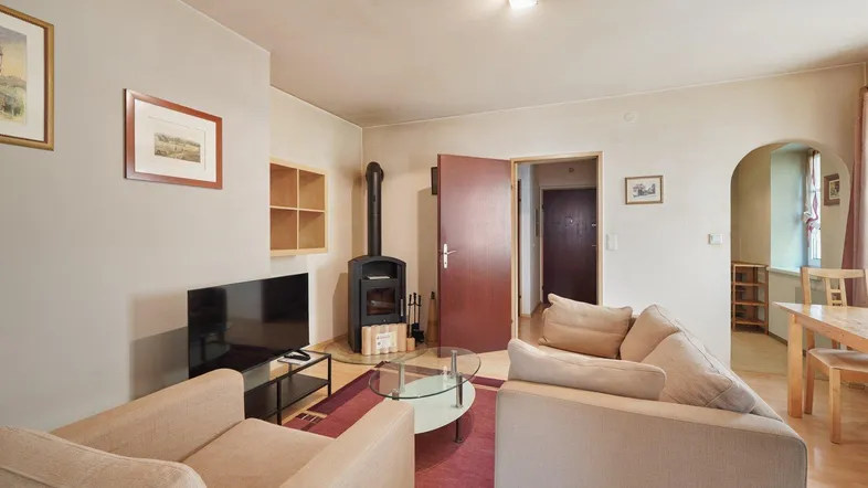 Gemütliches Wohnzimmer mit Holzofen, beigen Sofas und einem Essbereich im Hintergrund.
