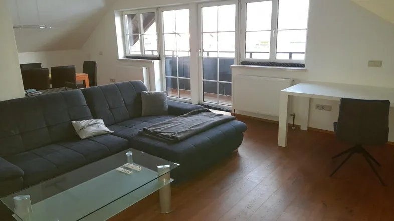 Helles Wohnzimmer mit gemütlichem Sofa, Schreibtisch und Zugang zu einem französischen Balkon.