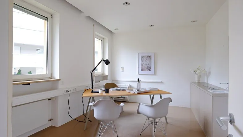 Helles Büro mit Schreibtisch, modernen Stühlen und großen Fenstern für viel Tageslicht.