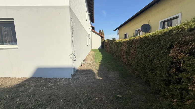 Seitenansicht des Hauses mit einer hohen Hecke, die Privatsphäre bietet.