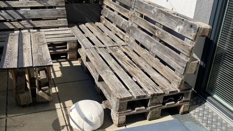 Gemütliche Terrasse mit selbstgebauten Palettenmöbeln und Pflanzen, ideal zum Entspannen im Freien.