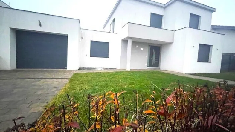 Modernes Einfamilienhaus mit weißer Fassade, Garage und gepflegtem Vorgarten.