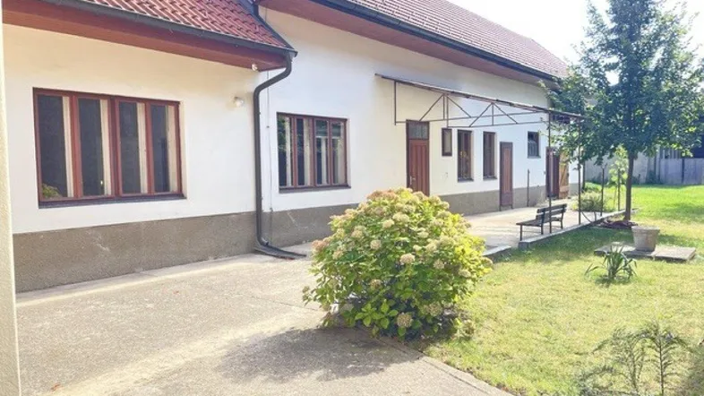 Ländliches Haus mit weißer Fassade, rotem Ziegeldach und einem gepflegten Vorgartenbereich.