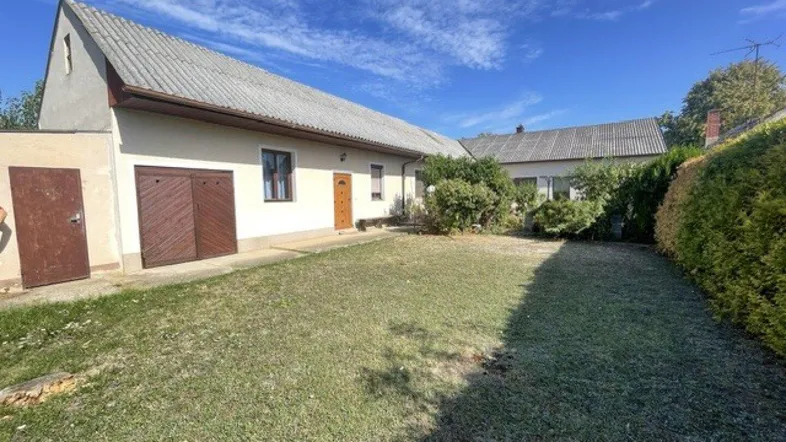 Geräumiger Gartenbereich mit Rasenfläche und Blick auf das traditionelle Wohnhaus mit Garage.