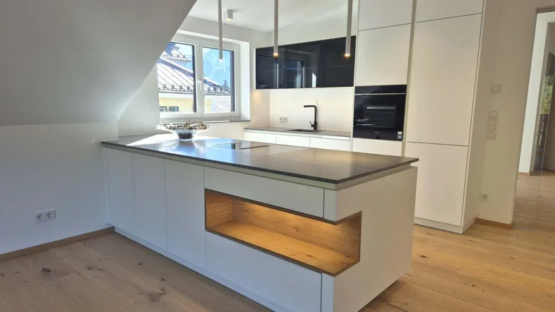 Moderne Küche mit integrierter Kücheninsel, hochwertigen Geräten und viel Stauraum.
