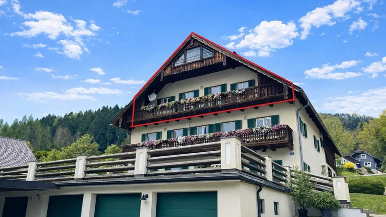 Traditionelles Haus mit Satteldach, Balkonen und integrierter Garage in grüner Umgebung.