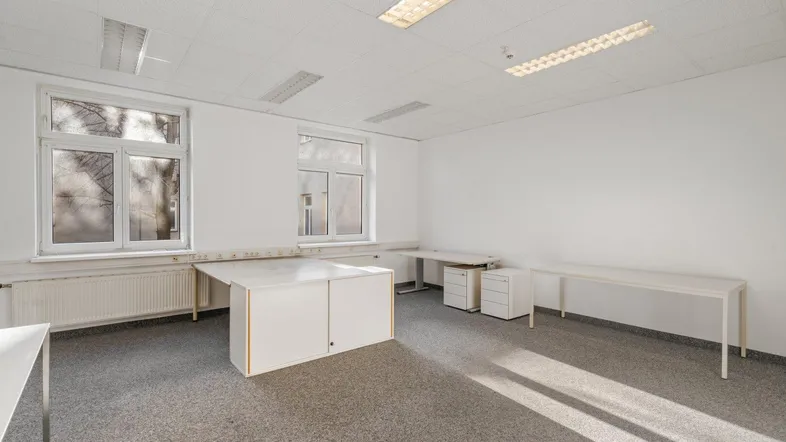 Helles Büro mit Teppichboden, großen Fenstern und funktionalen Büromöbeln, ideal für produktives Arbeiten.