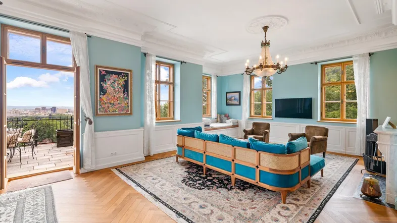 Helles Wohnzimmer mit elegantem Sofa, Kamin und Zugang zu einer großen Terrasse mit Stadtblick.