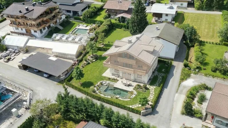 Luftaufnahme eines gepflegten Chalets mit großem Garten, Teich und Außenbereich in ländlicher Umgebung.