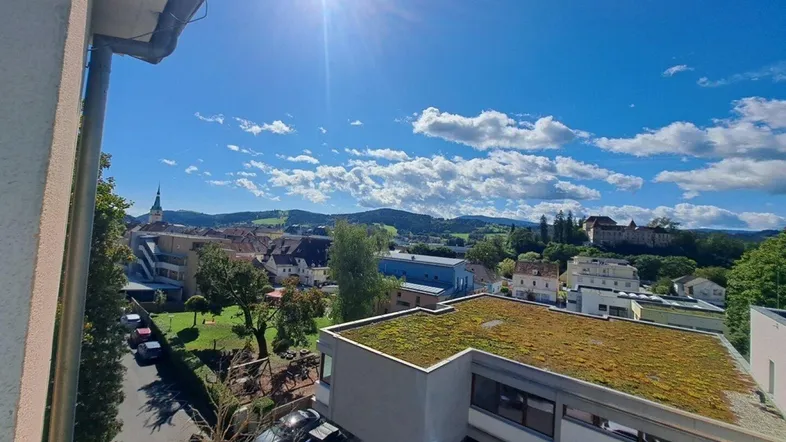 Panoramablick über die Stadt und die umliegende Natur unter strahlend blauem Himmel.