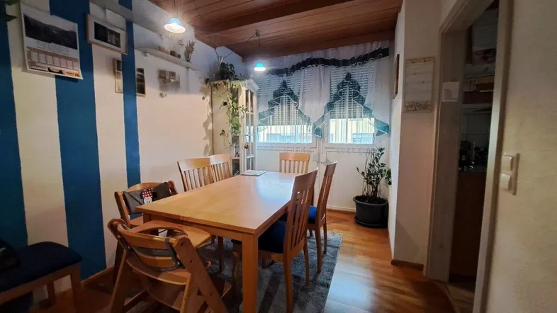 Gemütlicher Essbereich mit Holztisch, Holzdecke und gestreiften Wänden, ideal für Familienmahlzeiten.