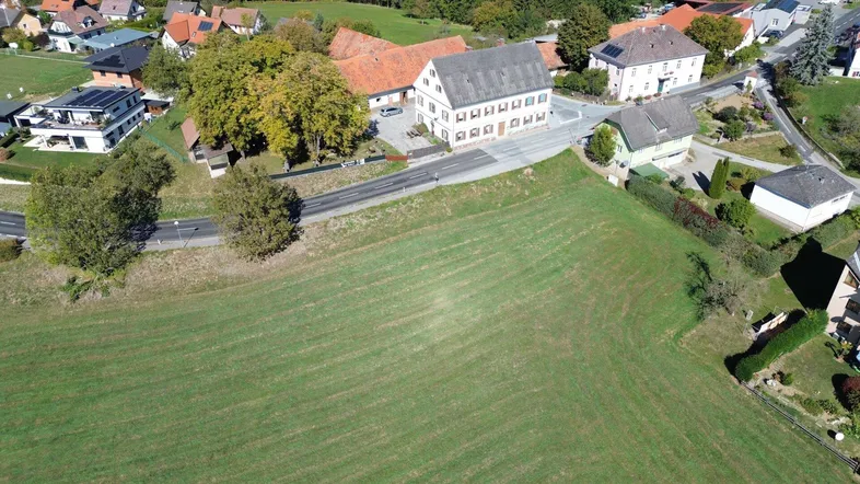 Luftaufnahme eines ländlichen Anwesens mit einem großen Feld, umgeben von Straßen und weiteren Häusern.