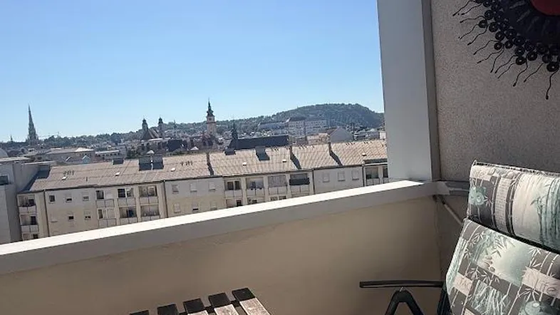 Gemütlicher Balkon mit Markise, Sitzgelegenheiten und weitem Blick über die Stadt.