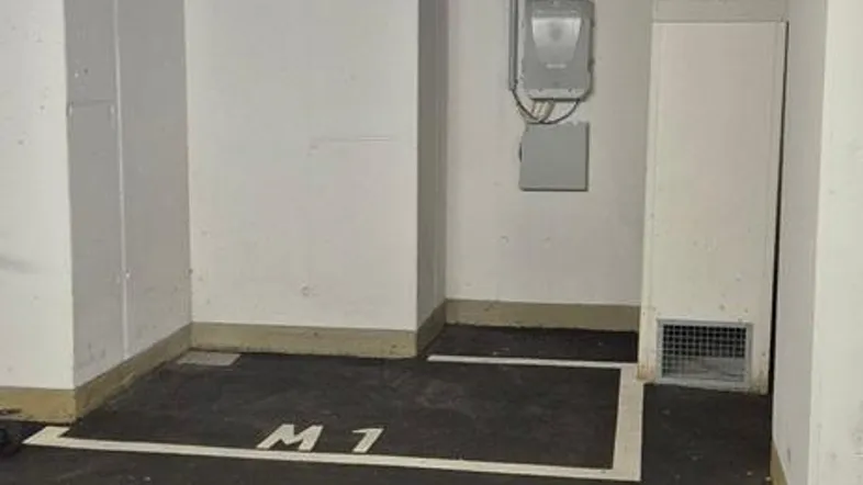 Tiefgaragenstellplatz M1 mit sichtbaren Leitungen und Rohren an der Decke.