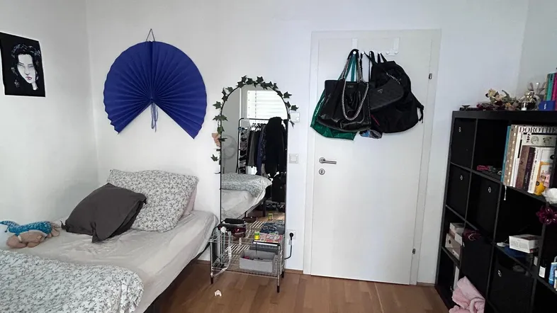 Helles Schlafzimmer mit Holzboden, einem Bett und einem großen Spiegel.