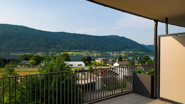 Geräumiger Balkon mit Fliesenboden und atemberaubendem Blick auf den See und die umliegenden Berge.