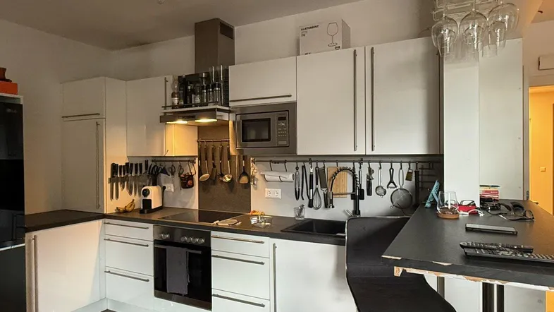 Moderne Küche mit weißen Schränken, dunkler Arbeitsplatte und integrierter Bar für schnelles Essen.