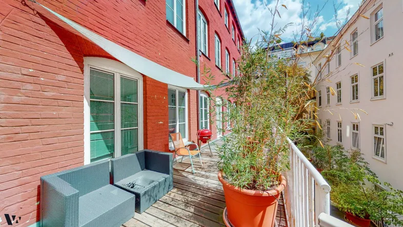 Geräumige Terrasse mit Sitzgelegenheiten, Pflanzen und einem Grill, umgeben von roten Backsteinmauern.