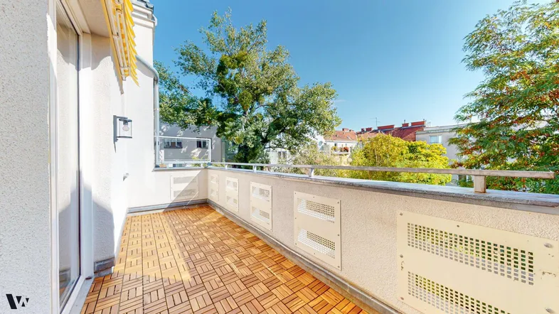 Heller Balkon mit Holzbodenfliesen und Blick ins Grüne, ideal für entspannte Stunden im Freien.
