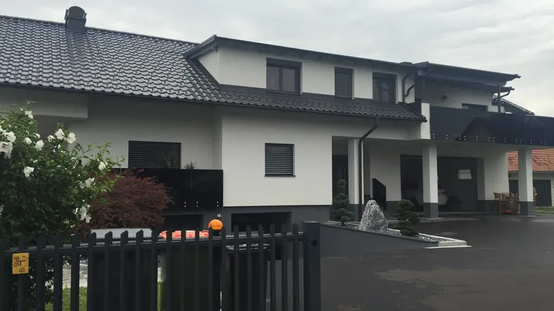 Modernes Einfamilienhaus mit weißer Fassade, dunklem Dach und gepflegter Auffahrt.