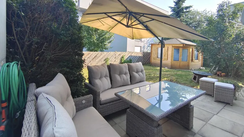 Gemütliche Terrasse mit Outdoor-Sitzgruppe, Sonnenschirm und Blick auf den Garten mit Gartenhaus.
