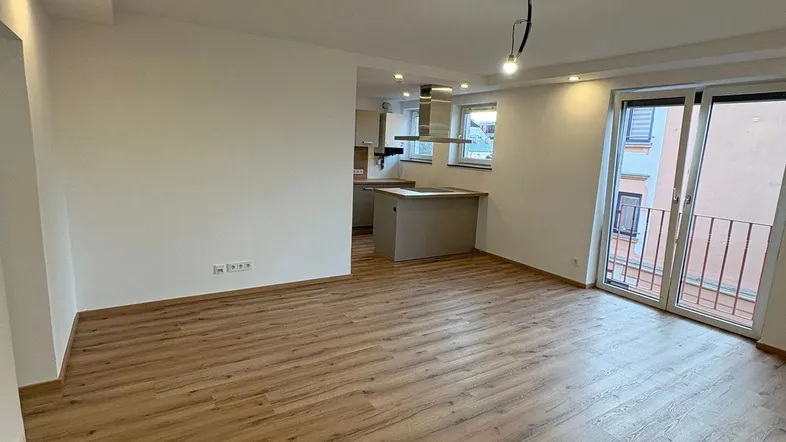 Heller Wohn- und Essbereich mit modernem Laminatboden und Zugang zu einem französischen Balkon.