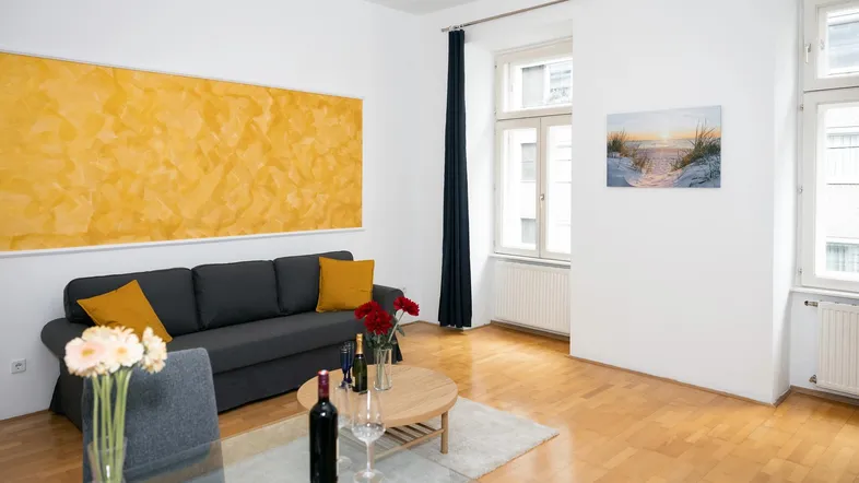 Helles Wohnzimmer mit Parkettboden, bequemer Couch und dekorativer gelber Wandgestaltung.