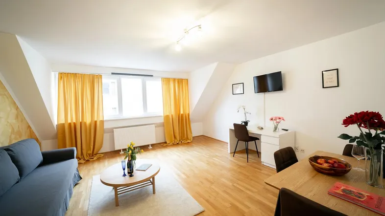 Helles Wohn- und Esszimmer mit Holzboden, Dachschrägen und einem Arbeitsbereich.