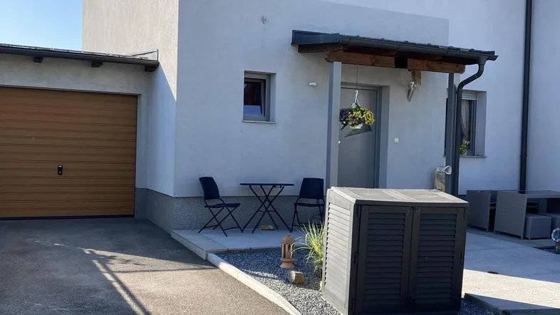 Modernes Einfamilienhaus mit heller Fassade, Garage und kleinem Vorgartenbereich.