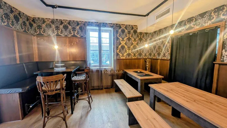 Gemütlicher Restaurantbereich mit dunkler Tapete, Holzvertäfelung und verschiedenen Sitzgelegenheiten unter warmem Licht.