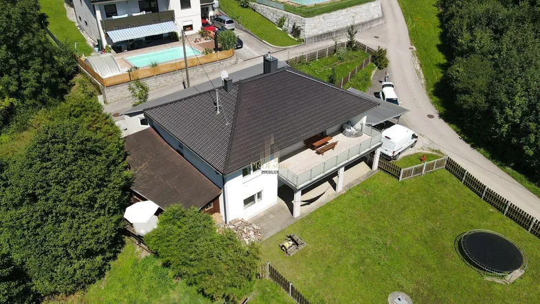 Luftaufnahme eines Einfamilienhauses mit großem Garten, Terrasse und umliegender Natur.