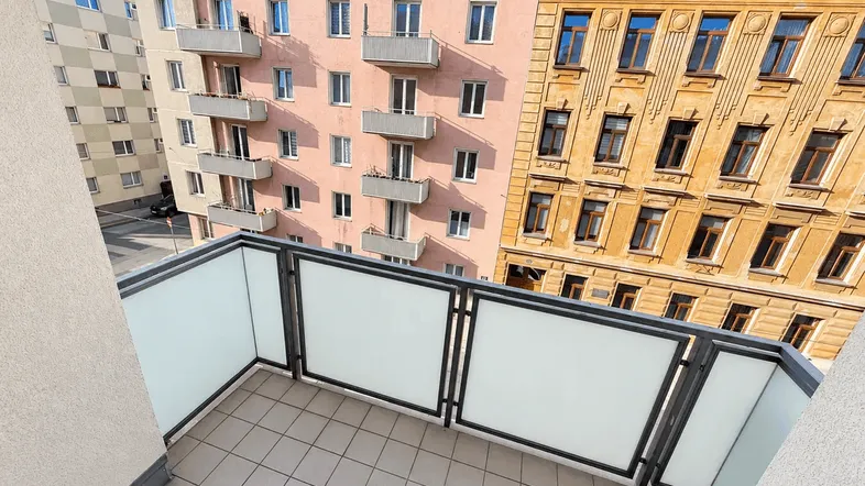 Balkon mit Fliesenboden und Blick auf die umliegenden Wohngebäude in der Stadt.