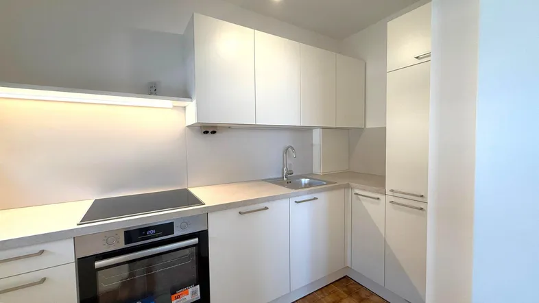 Moderne Einbauküche mit weißen Hochglanzfronten, Induktionskochfeld und integriertem Backofen.