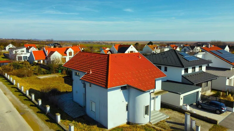 Luftaufnahme eines Einfamilienhauses mit rotem Dach in einer ländlichen Siedlung.