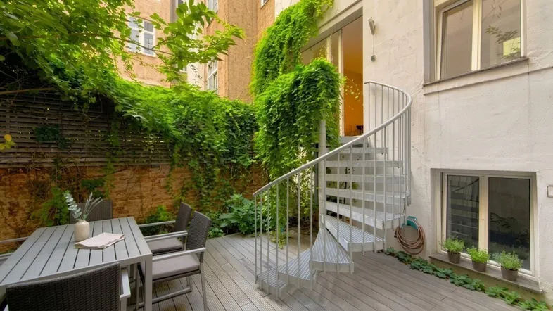 Gemütliche Terrasse mit Holzdeck, Sitzbereich und einer eleganten Wendeltreppe.