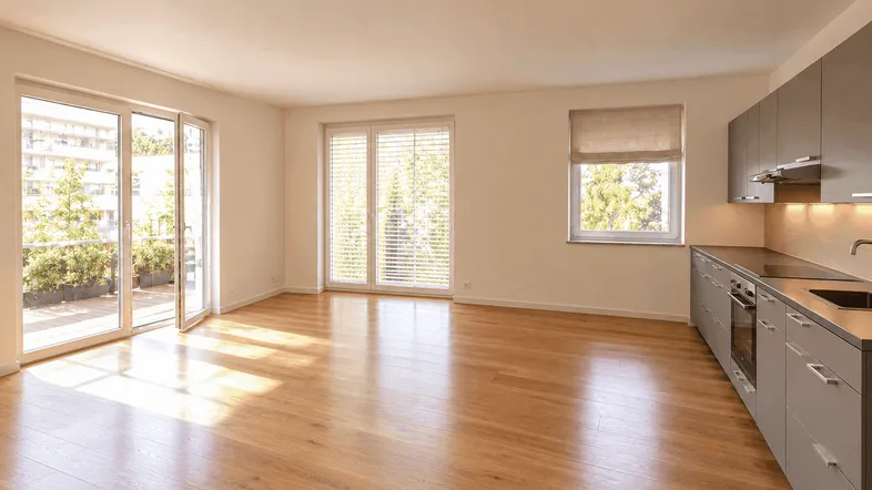 Helles Wohnzimmer mit integrierter Küchenzeile, Holzboden und Zugang zur Terrasse.