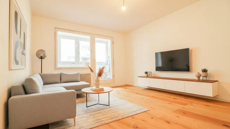 Modern eingerichtetes Wohnzimmer mit bequemer Couch, Fernseher und Holzboden.